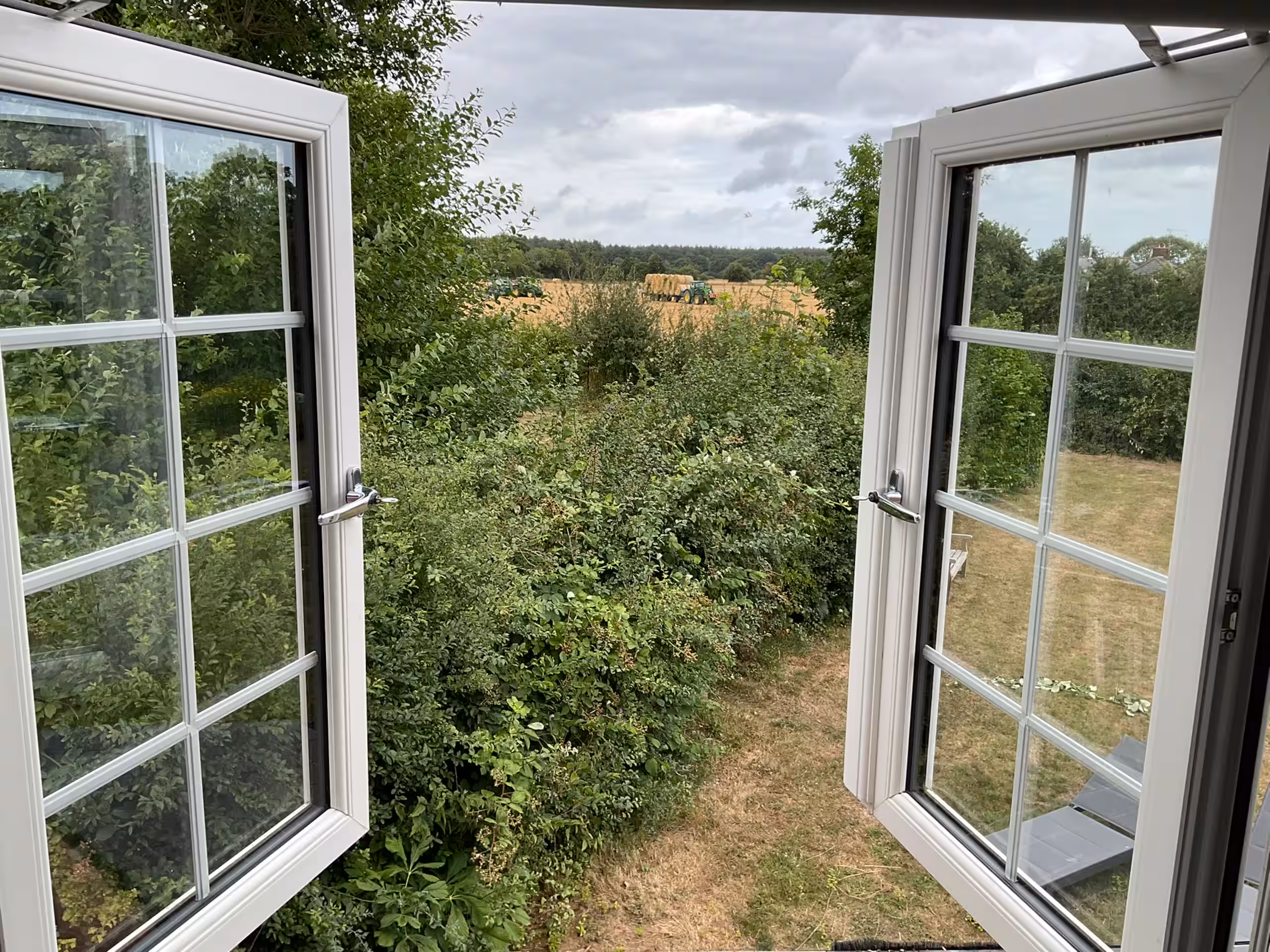 Open casement windows framing the Kent farmland view